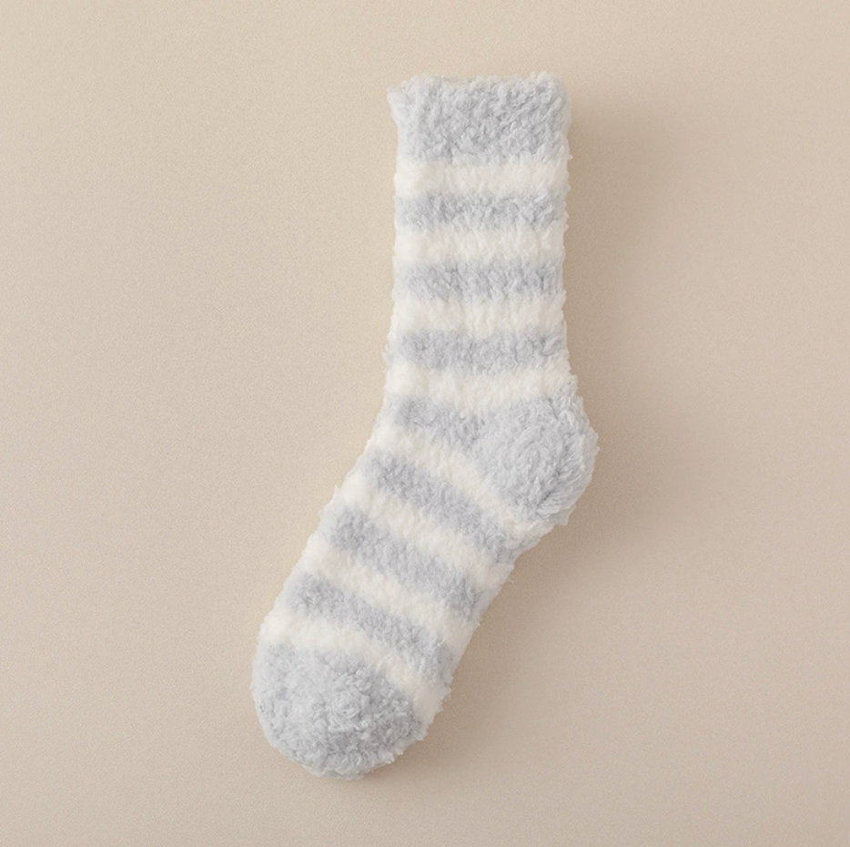 Best sleeping socks for cold feet in ivory and pale-grey plush, featuring a gently striped cuff. Photographed upright from the side to show the cozy pile.
