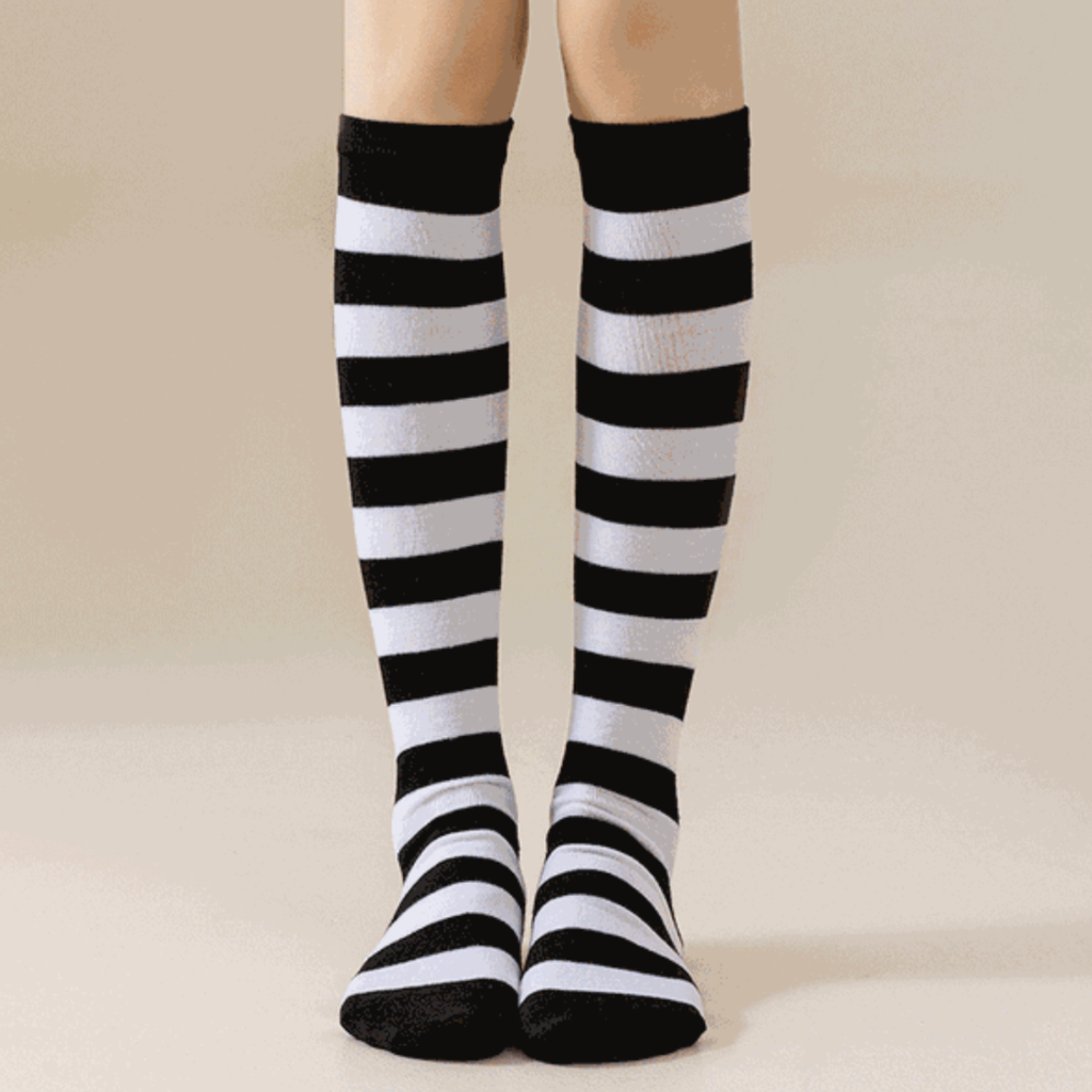 Black and white striped knee socks in classic wide stripes, featuring a stretchy leg. Worn on legs against a neutral backdrop.