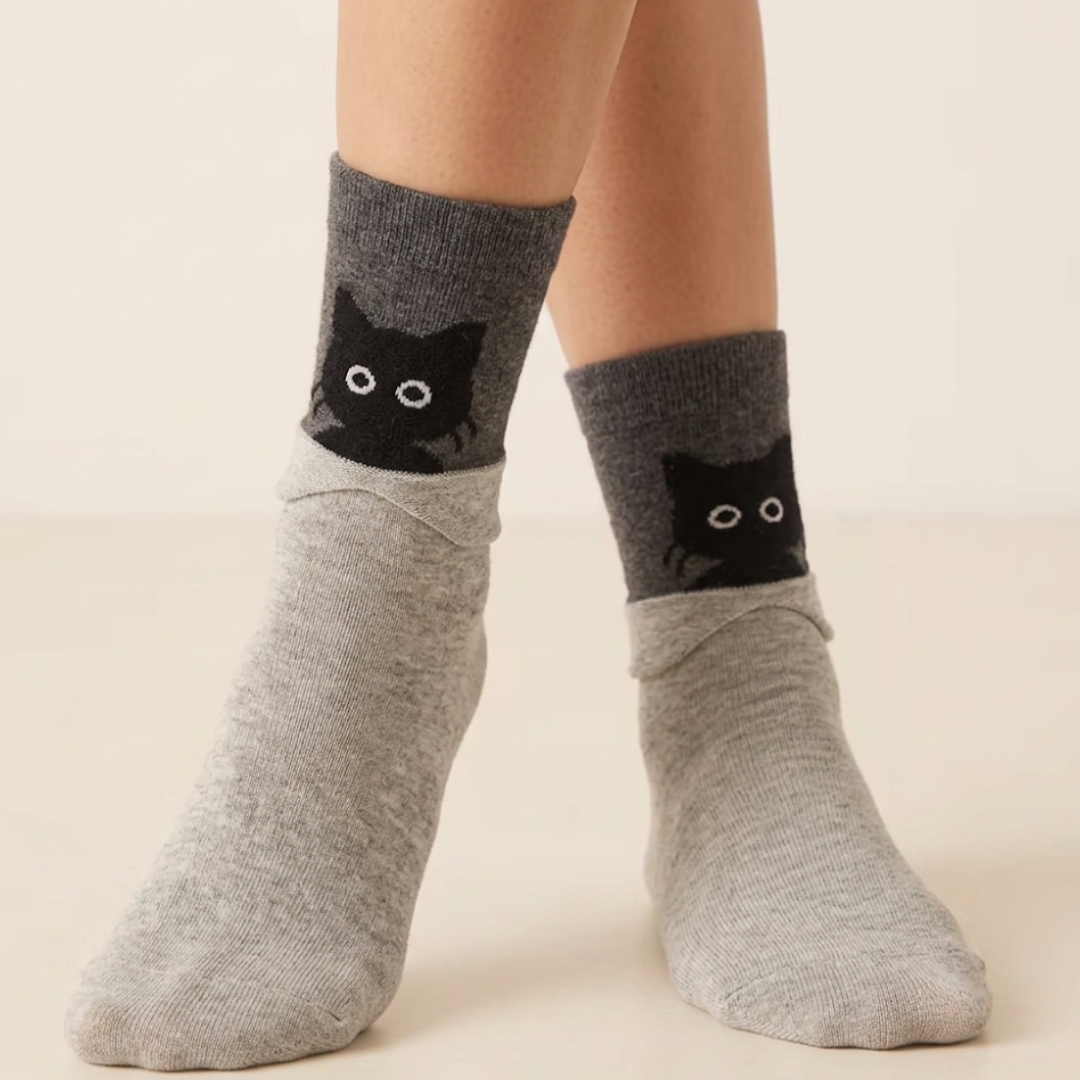 Black cat socks in gray with a black cat face peeking over the cuff, worn on the feet.