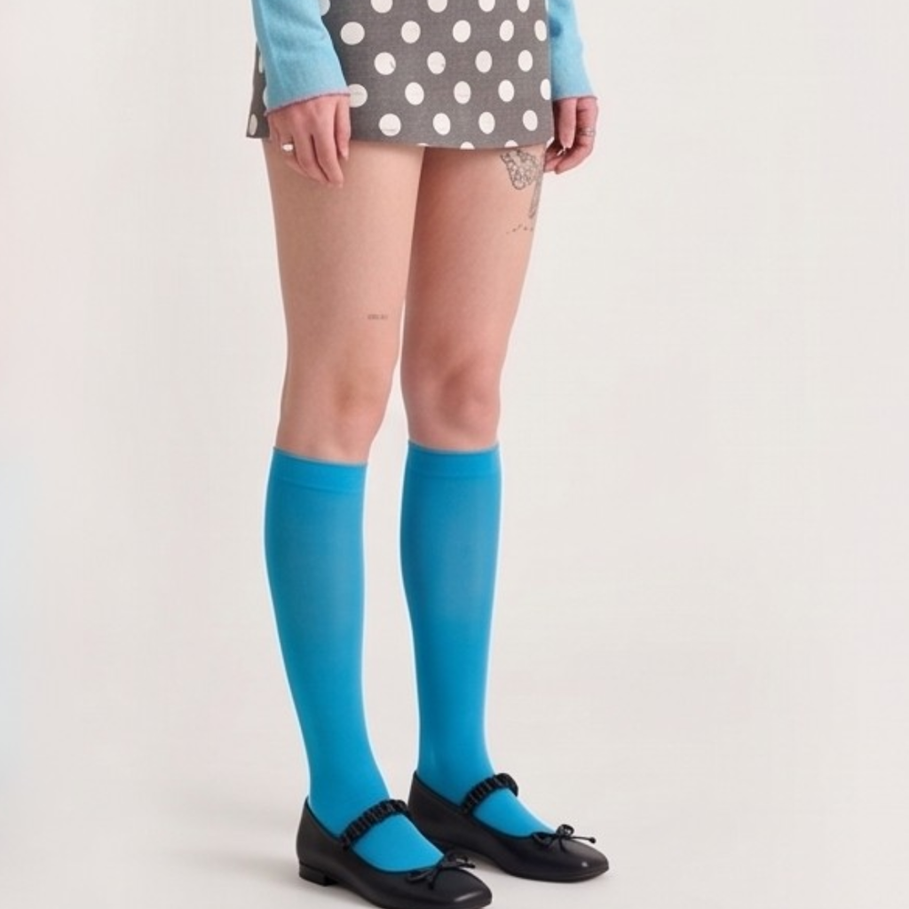 Blue fashion knee socks in bright blue sheer knit, featuring a smooth leg. Worn with a polka-dot skirt.