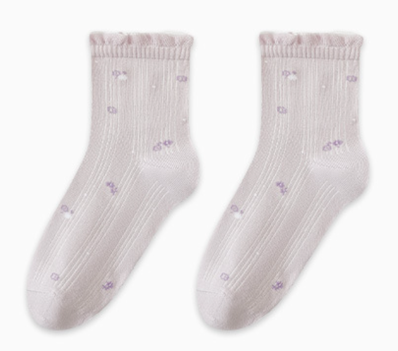 Breathable socks for sleeping in white cotton, featuring tiny floral embroidery and a ruffle trim. Displayed as a flat-lay pair on a light backdrop.