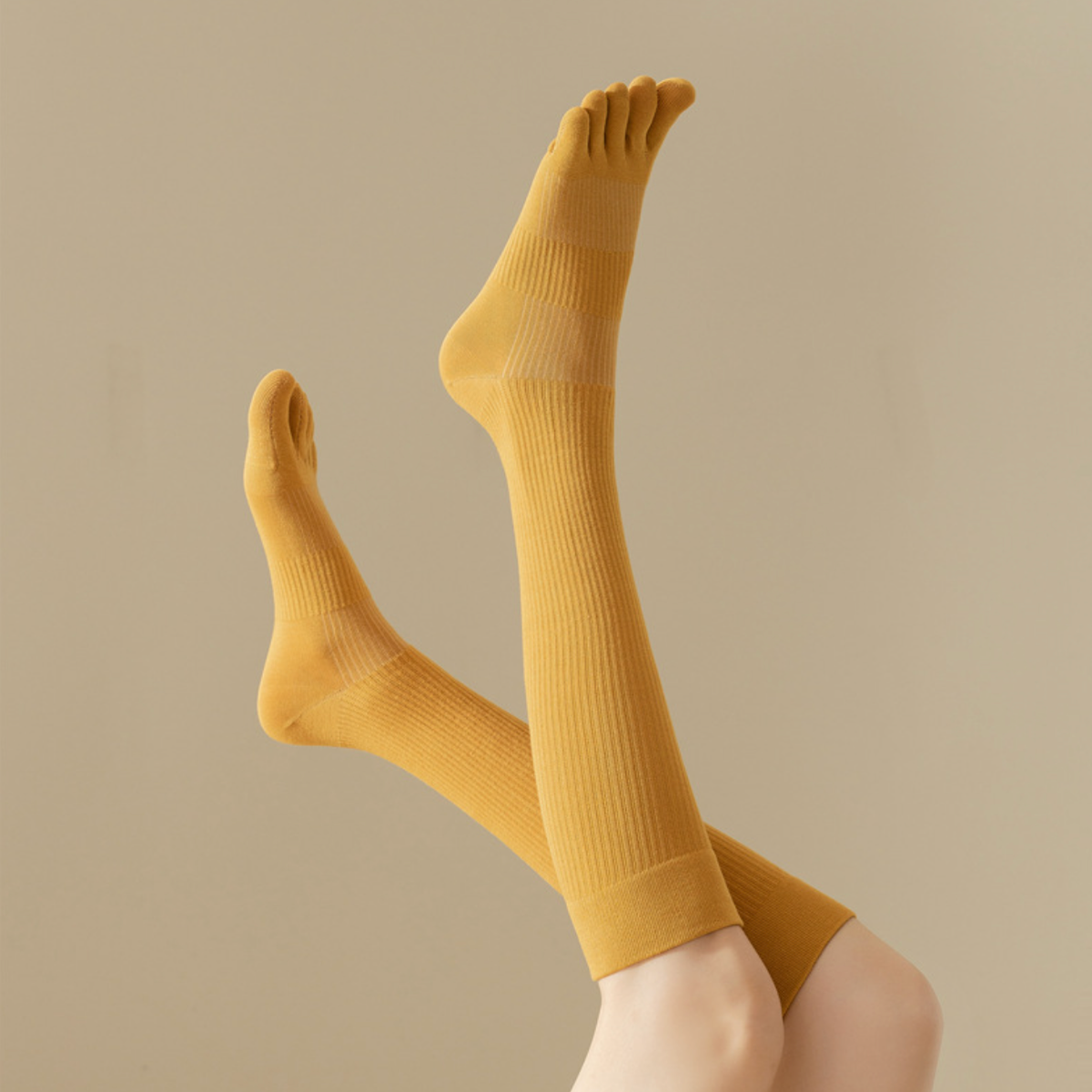 Compression toe socks in mustard yellow ribbed knit, featuring individual toe pockets. Worn on crossed legs.