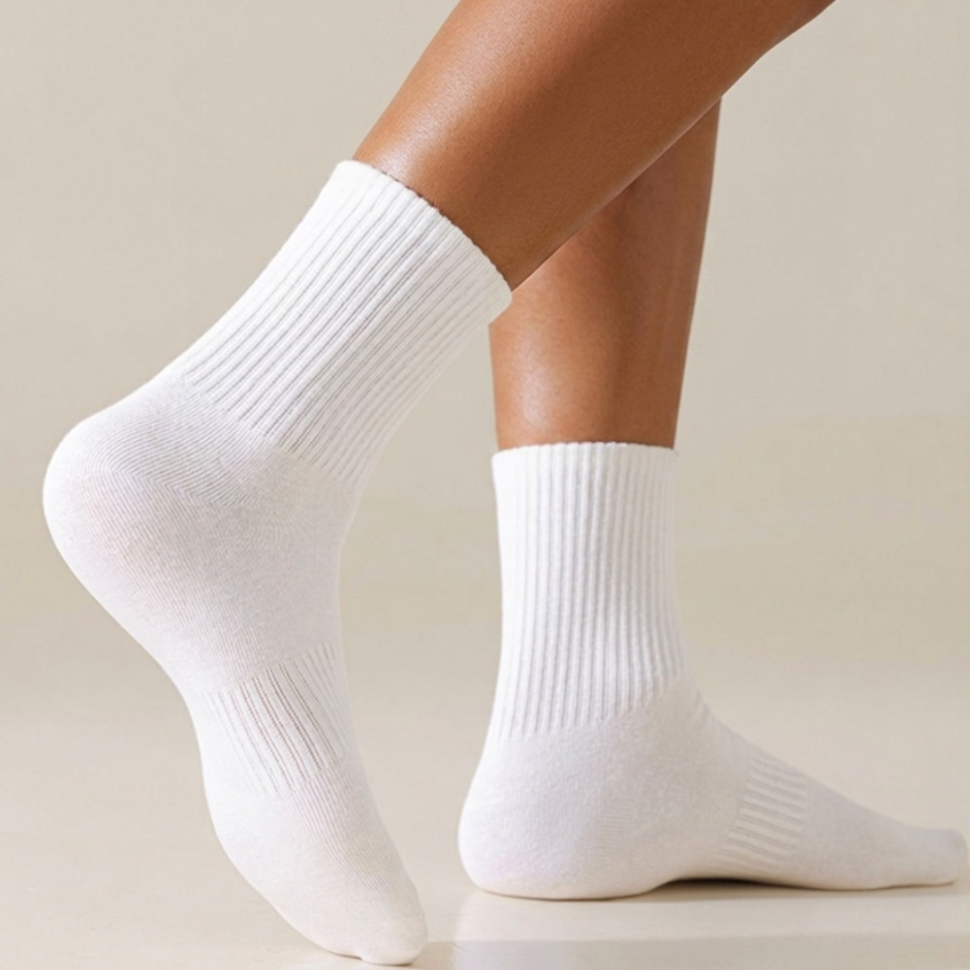 Cotton crew socks in white ribbed cotton, featuring a soft crew cuff. Worn on the feet in a light setting.