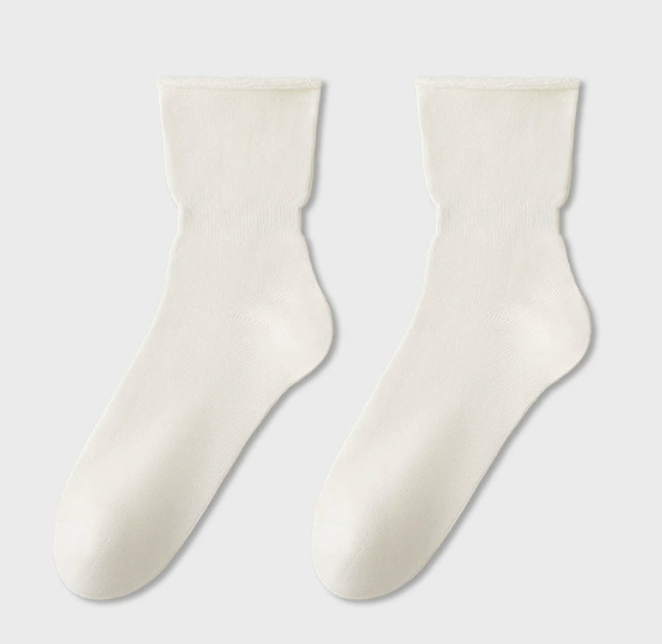 Cotton sleep socks in ivory cotton, featuring a smooth ribbed knit. Laid flat as a pair against a light backdrop.