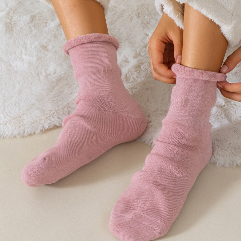 Cotton sleep socks in blush pink, featuring a soft cushioned foot. Shown worn on one foot with the cuff folded down.