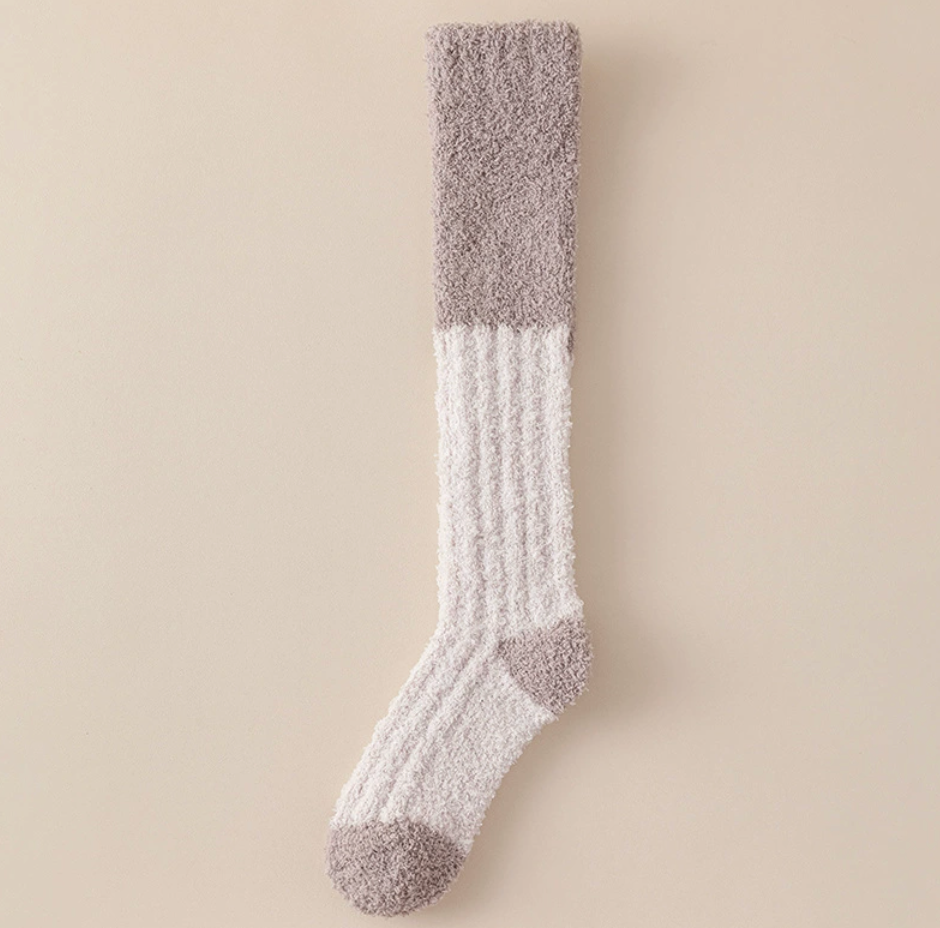 Cozy knee high socks in cream plush, featuring taupe colorblock cuffs. Laid flat against a light backdrop.