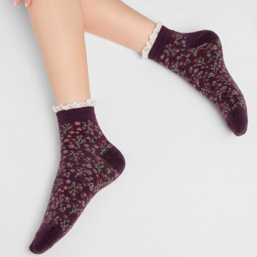 Cute ankle socks in berry purple with a ditsy floral print and lace trim, worn on the feet.