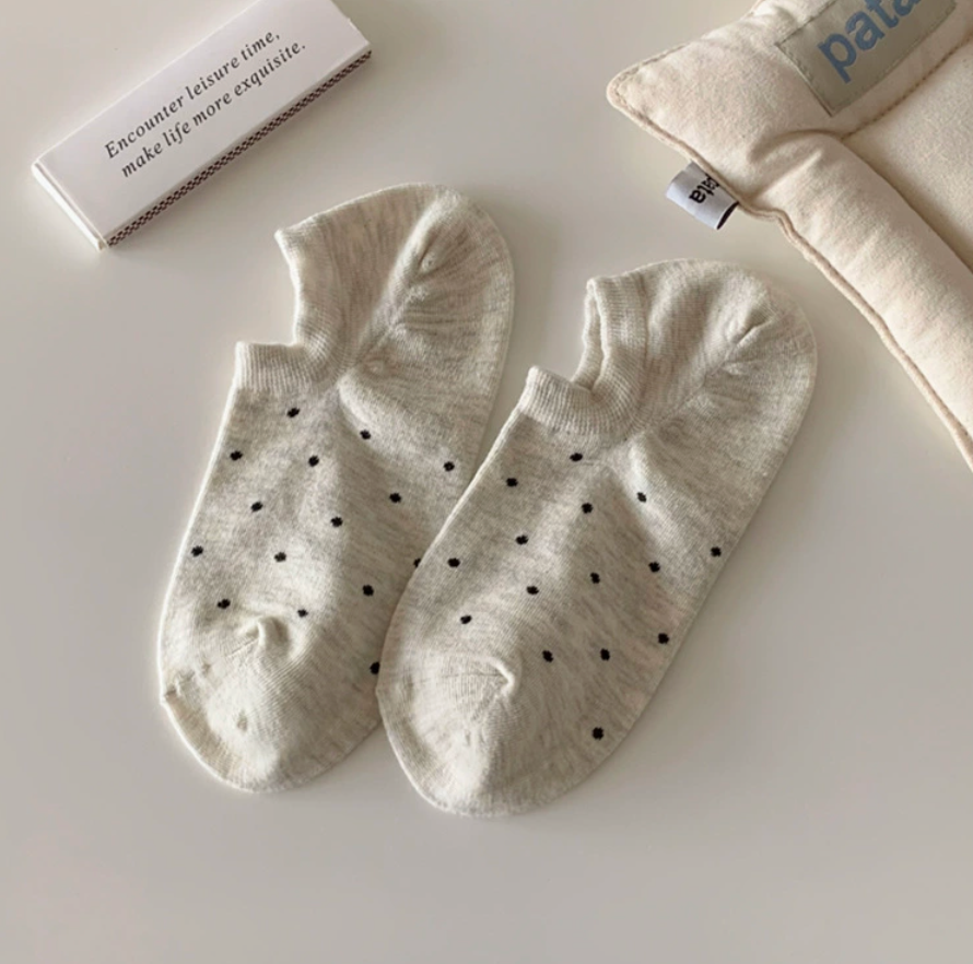 Cute ankle socks in ivory with polka dots, featuring a ruffled frill trim. Displayed flat as a pair on a light backdrop.