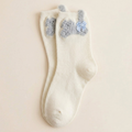 Cute cat socks in ivory white with fuzzy cat ears and pompoms, single sock laid flat.