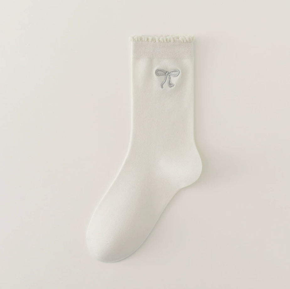 Cute crew socks in cream knit, featuring a bow accent and frilled cuff. Displayed as a single flat-lay.