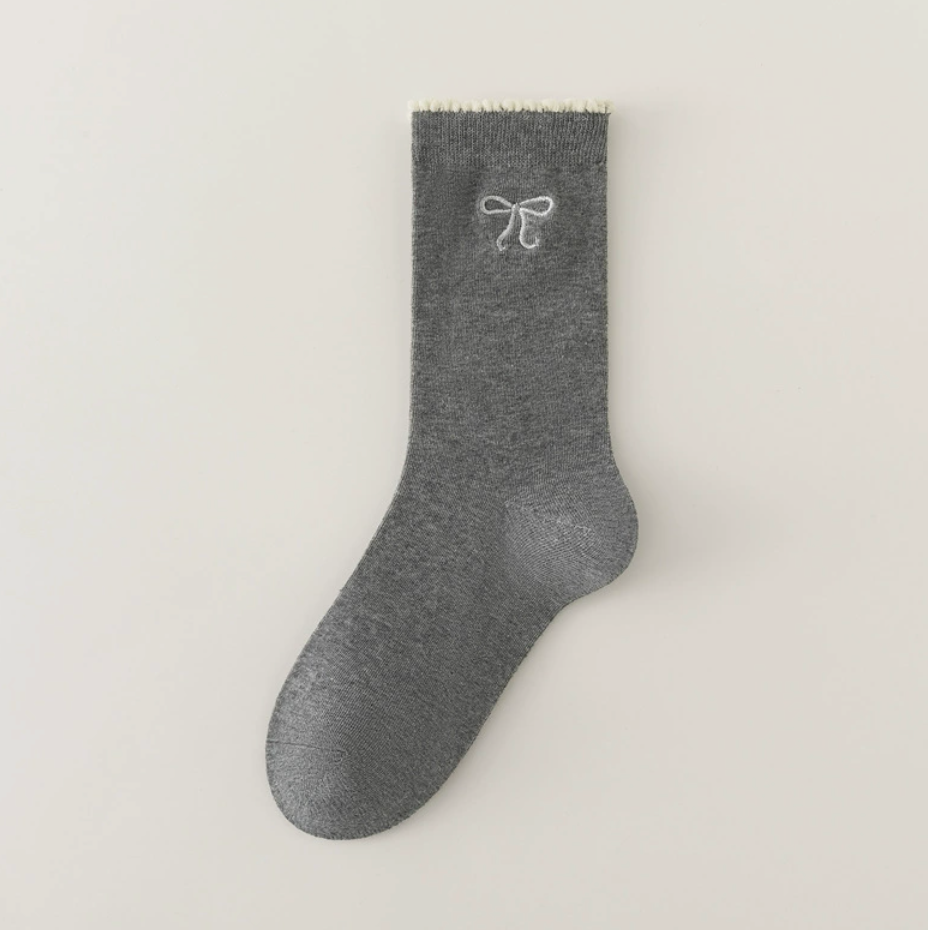 Cute crew socks in grey knit, featuring a bow embroidery. Shown as a single flat-lay on a light surface.