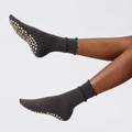 Cute grip socks in dark gray with a dotted silicone non-slip sole, worn on the feet.