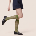 Cute knee high socks in olive green sheer knit, featuring a subtle pattern. Styled with a navy skirt and loafers.
