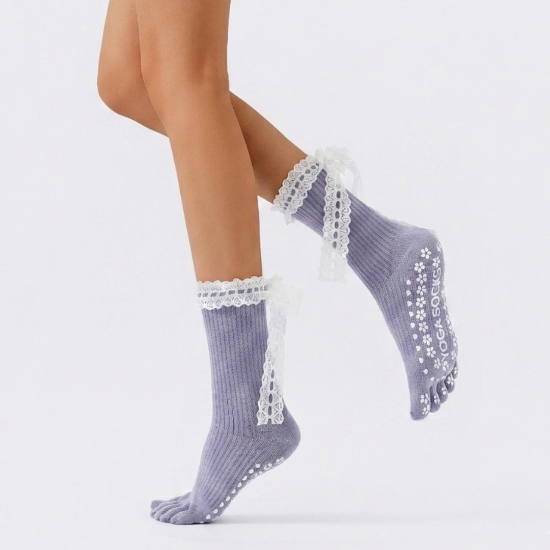 Cute pilates grip socks in lavender split-toe knit with a lace-up bow and non-slip sole, worn on the legs.