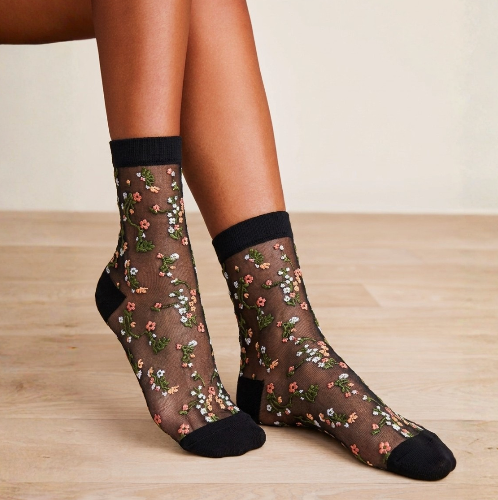 Cute sheer socks in floral mesh with a black cuff and toe, worn on the feet, side view.