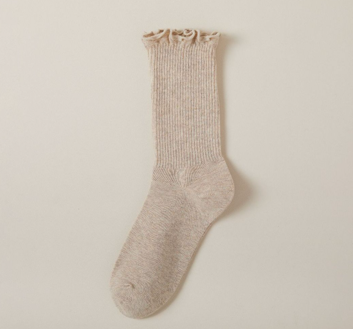 Cute socks for loafers in beige with a ruffle lettuce edge, a single sock displayed to show the ribbed knit.
