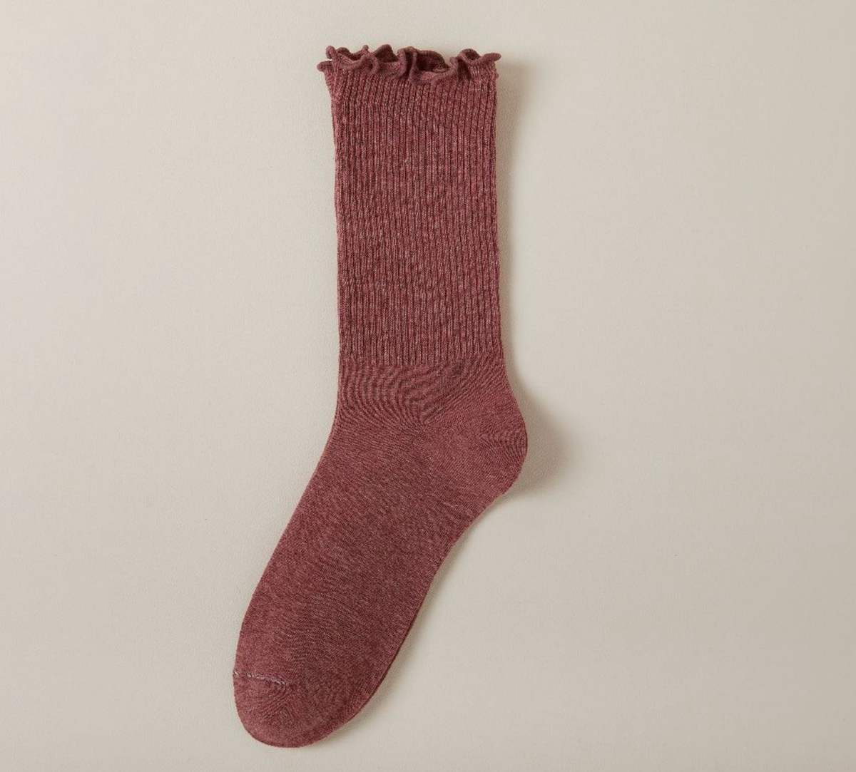 Cute socks for loafers in berry red with a ruffle cuff, a single sock highlighting the marled knit texture.