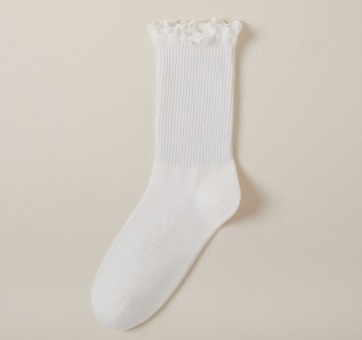 Cute socks for loafers in white with a ruffle trim, a single sock shown upright against a soft neutral backdrop.
