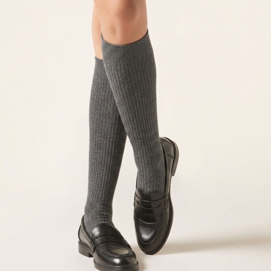 Dress socks for loafers in gray ribbed fine knit, worn over the calf with black leather loafers, side view.
