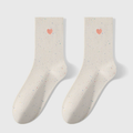 Embroidered crew socks in ivory knit, featuring a red heart embroidery. Shown as a flat-lay pair on a light backdrop.