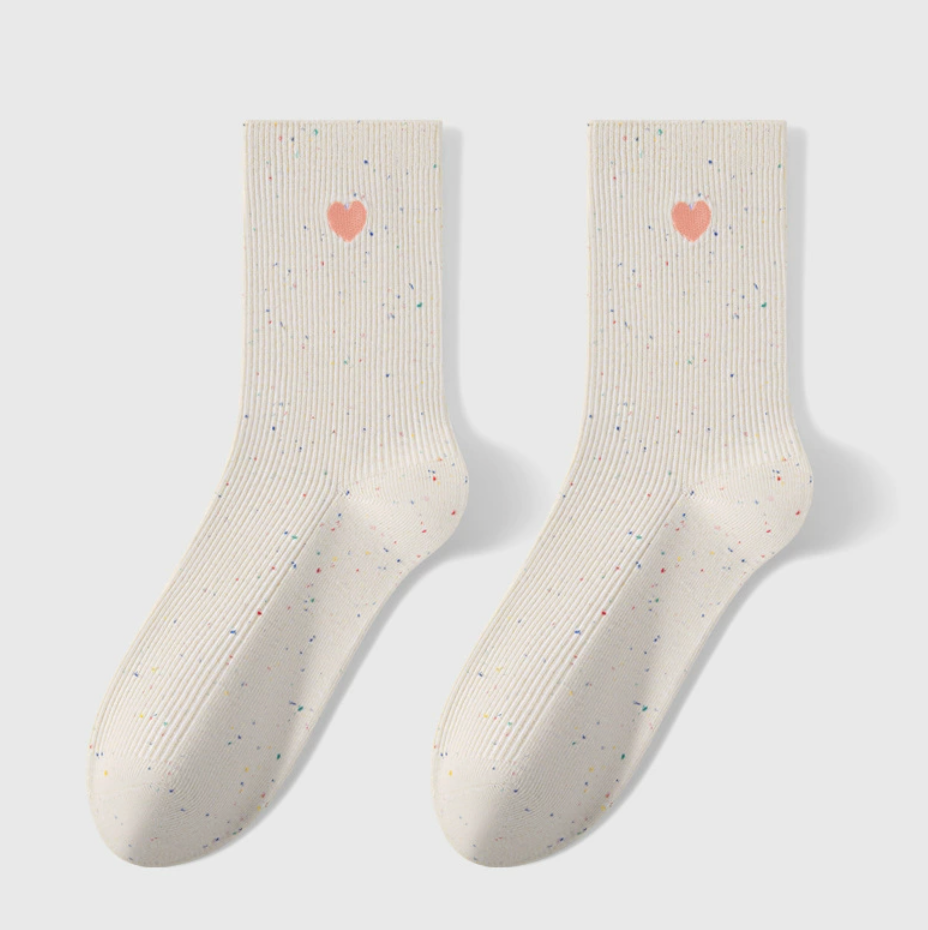 Embroidered crew socks in ivory knit, featuring a red heart embroidery. Shown as a flat-lay pair on a light backdrop.