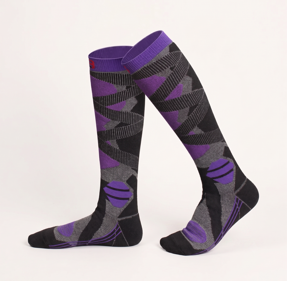 Equestrian boot socks in purple and black, featuring a bold geometric argyle pattern. Worn on legs in a riding-style look.
