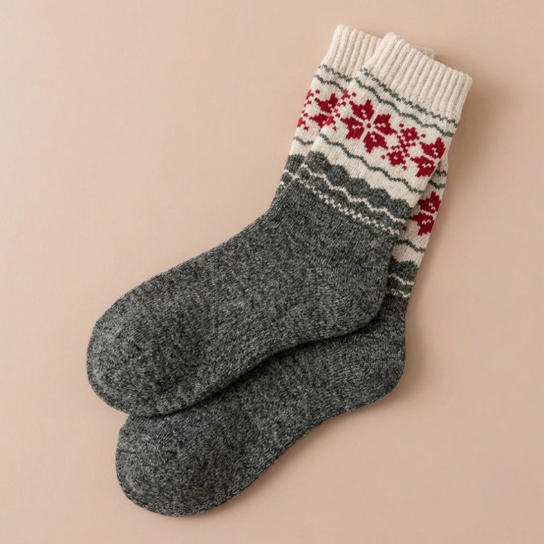 Fair isle Christmas socks in gray wool with a red snowflake band, flat-lay pair.