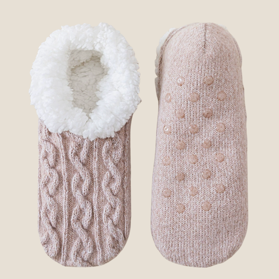 Fleece lined slipper socks in grey cable knit, featuring a fleece lining and gripped sole. Displayed flat as a pair on a light surface.