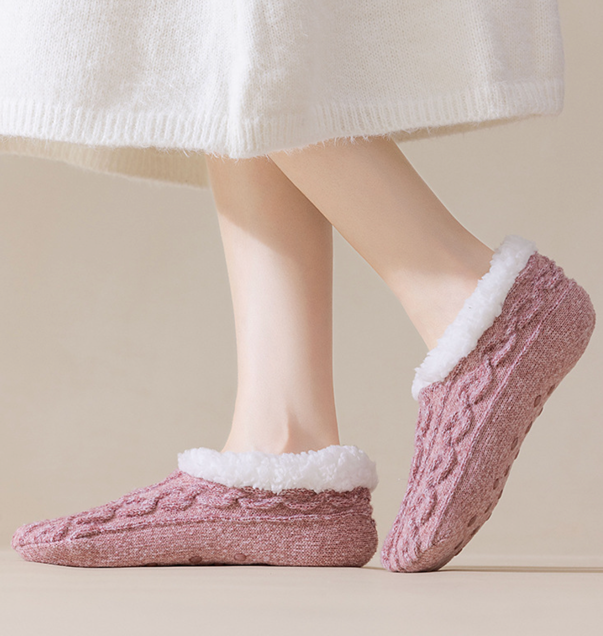 Fleece lined slipper socks in dusty pink cable knit, featuring a sherpa-lined cuff. Worn on feet in a cozy setting.