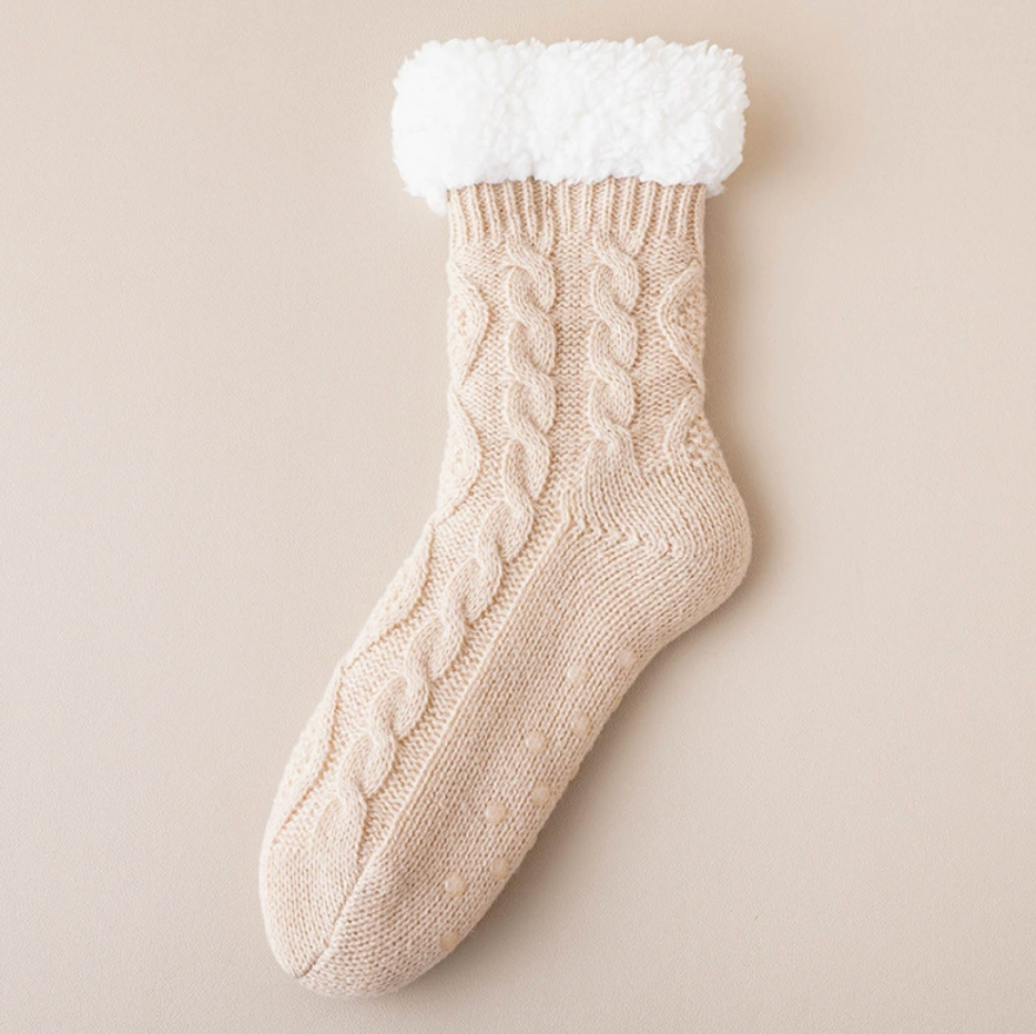 Fleece slipper socks in cream cable knit, featuring a soft sherpa cuff. Displayed flat on a light surface.