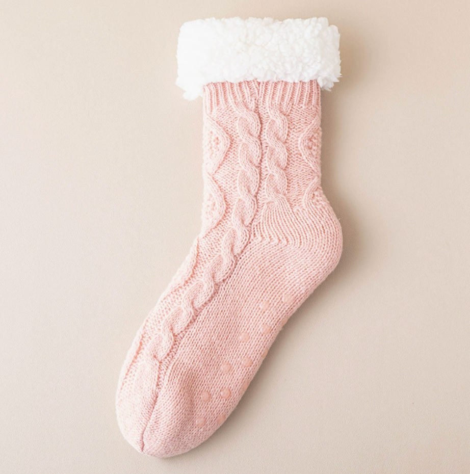 Fleece slipper socks in pink cable knit, featuring a fuzzy sherpa cuff. Shown as a single flat-lay on a neutral backdrop.