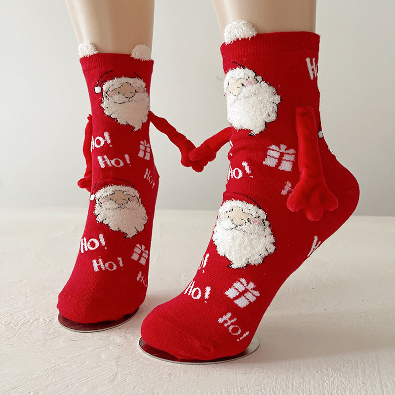 Funny Christmas socks in red with a Santa print and magnetic hands, shown holding hands on the feet.