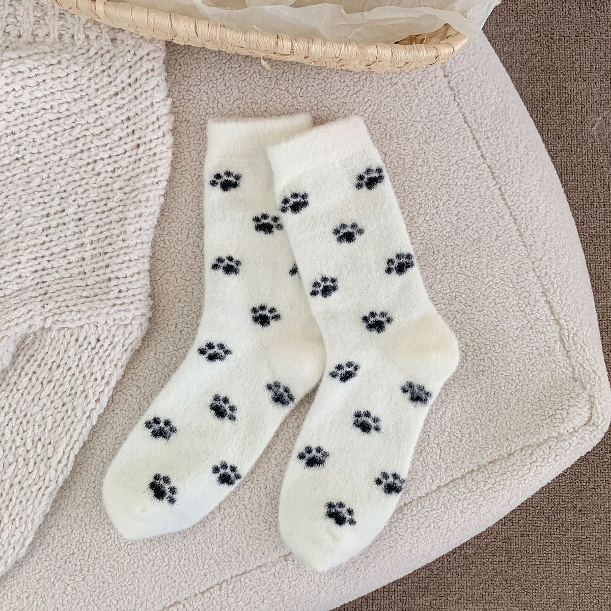 Fuzzy cat socks in white plush fleece with black cat-paw prints, flat-lay pair.