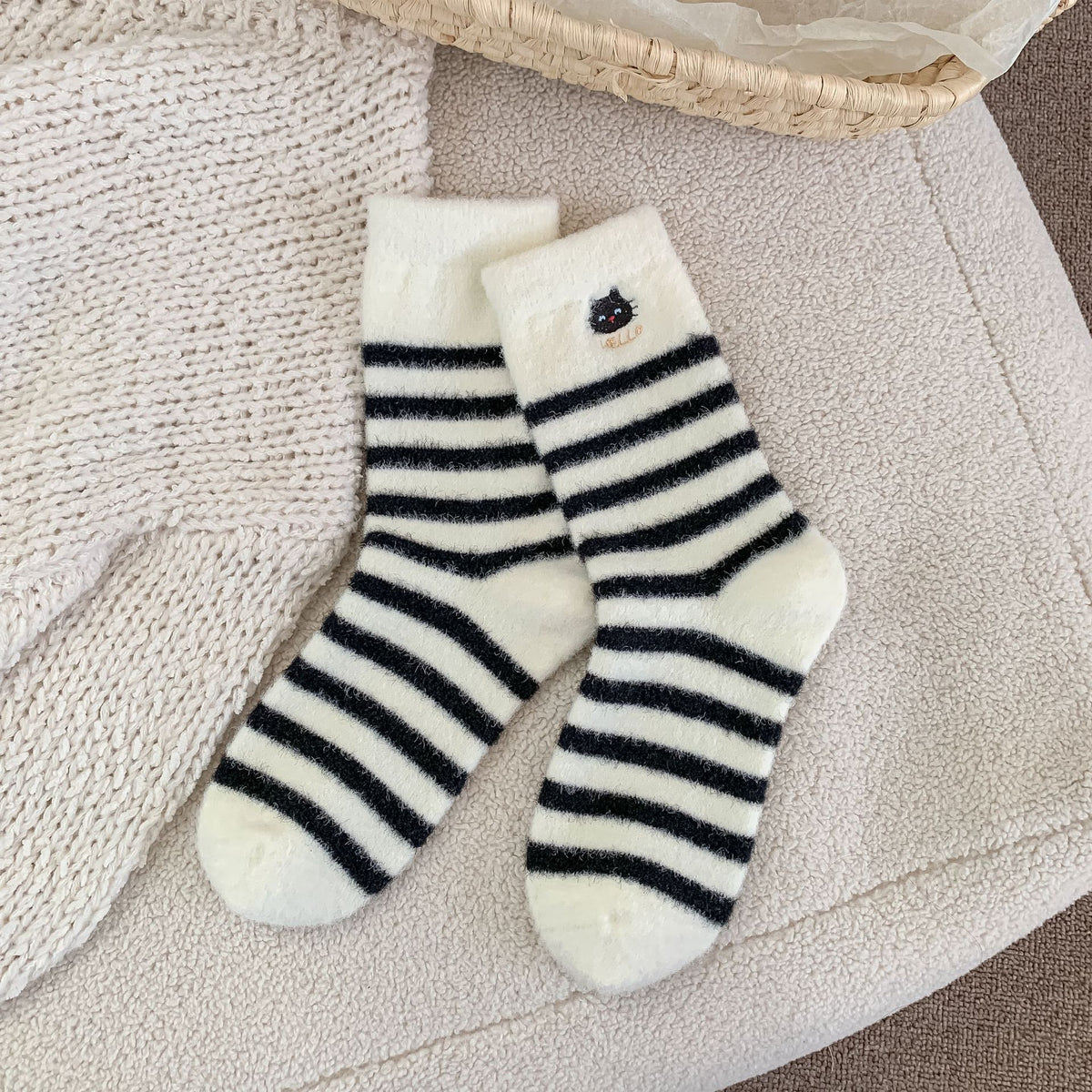 Fuzzy cat socks in white plush fleece with black stripes and a small cat, flat-lay pair.