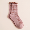 Girls' boot socks in soft pink, featuring a bow motif and frilled cuff. Shown as a flat-lay pair on a light surface.