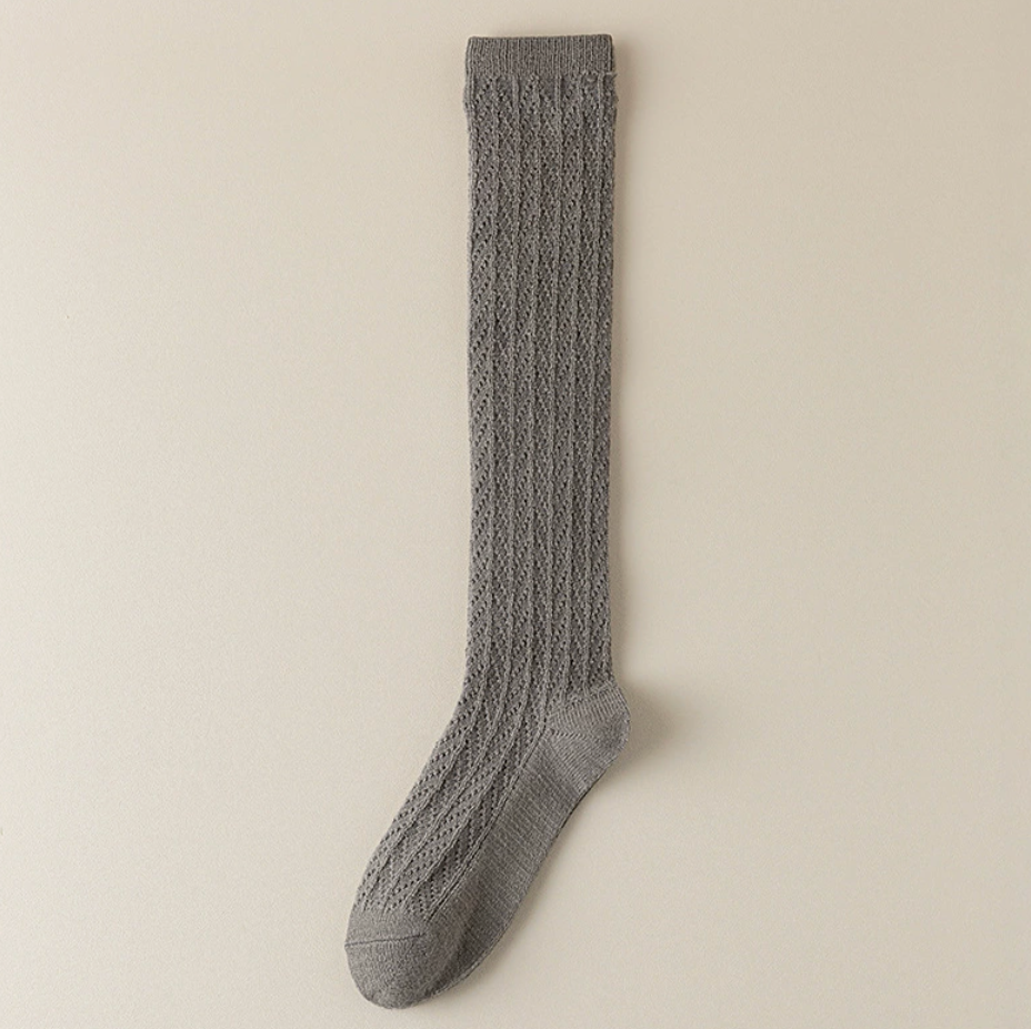 Gray knee socks for women in heather grey cable knit, featuring a textured weave. Shown as a single flat-lay on a neutral backdrop.