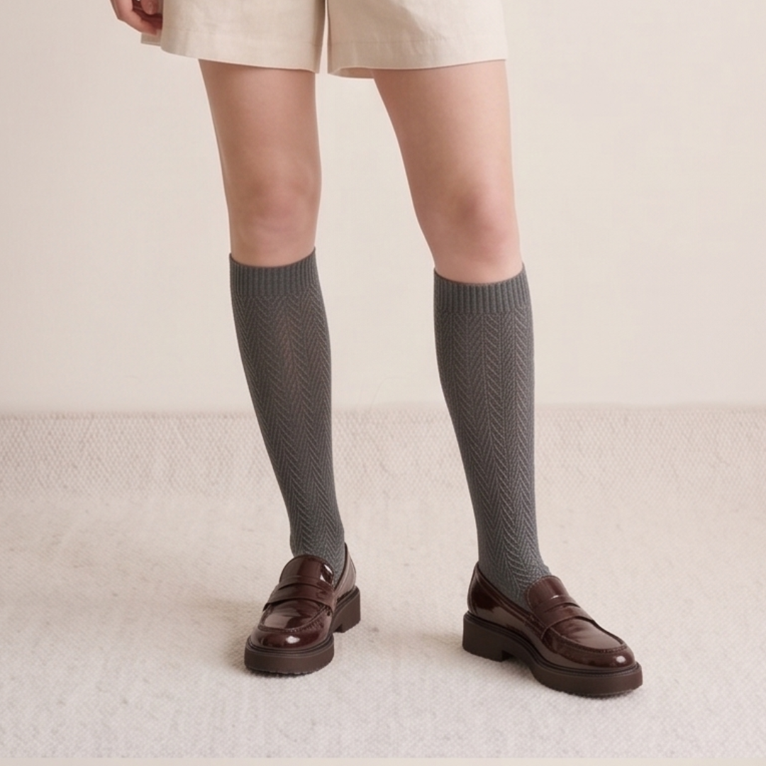 Gray knee socks for women in grey ribbed knit, featuring a soft cuff. Worn on feet with brown loafers.