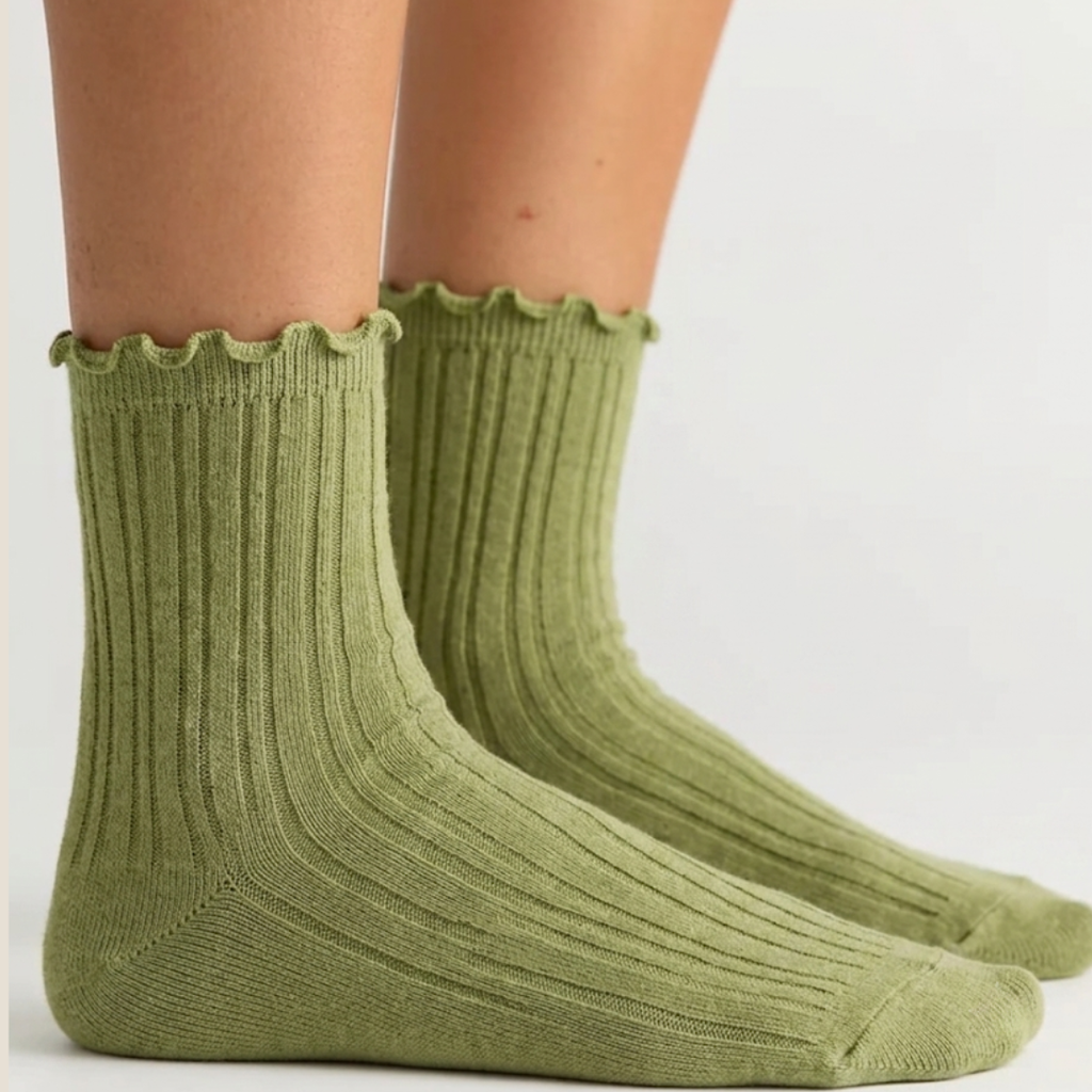 Green ruffle socks in olive green ribbed knit with a lettuce-ruffle cuff, worn on the feet, side view.