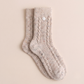 Heavyweight boot socks in oatmeal cable knit, featuring a cozy button-cuff detail. Displayed flat as a pair on a neutral backdrop.