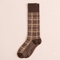 High boot socks in brown plaid, featuring a tartan check knit with a ribbed cuff. Shown as a single knee-high sock on a neutral backdrop.