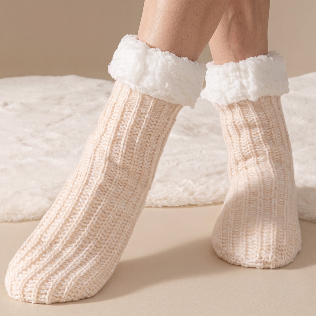 Hospital slipper socks in cream, featuring a non-slip gripped sole and sherpa cuff. Worn on feet to show the grip.
