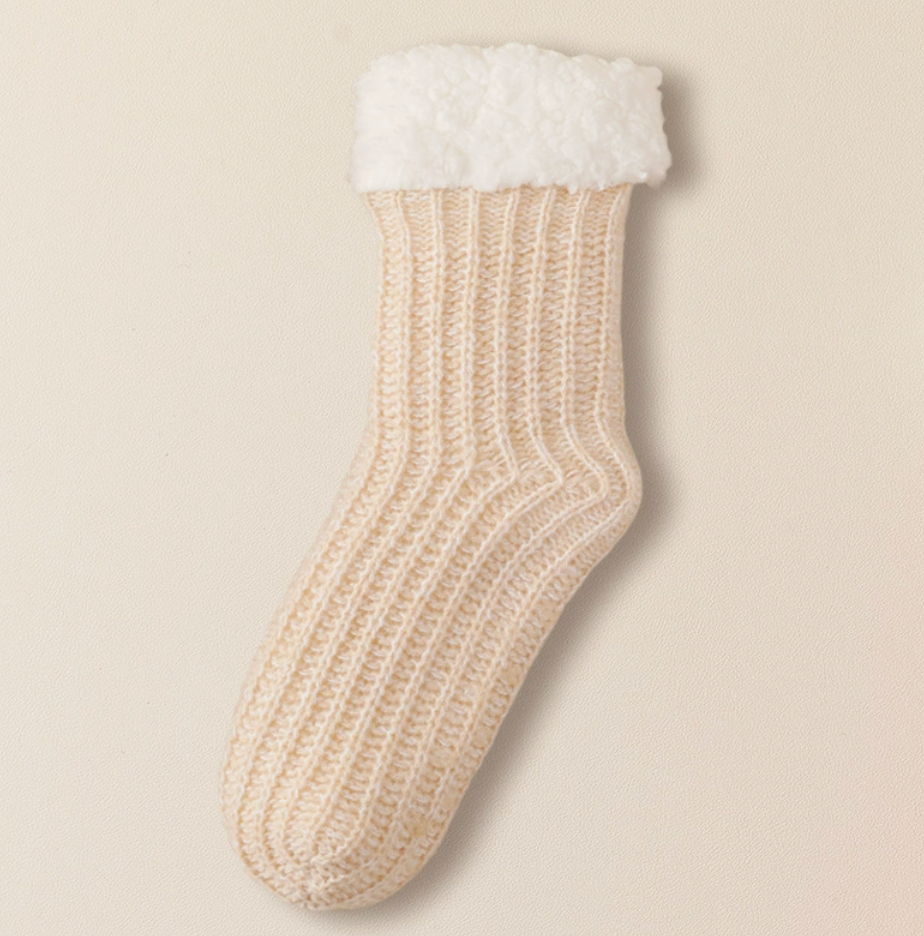 Hospital slipper socks in cream, featuring a fleece-lined sherpa cuff. Shown as a single flat-lay on a light backdrop.