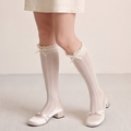 Knee high socks with bows in cream ribbed knit, featuring a bow accent at the cuff. Worn on legs in a sweet look.