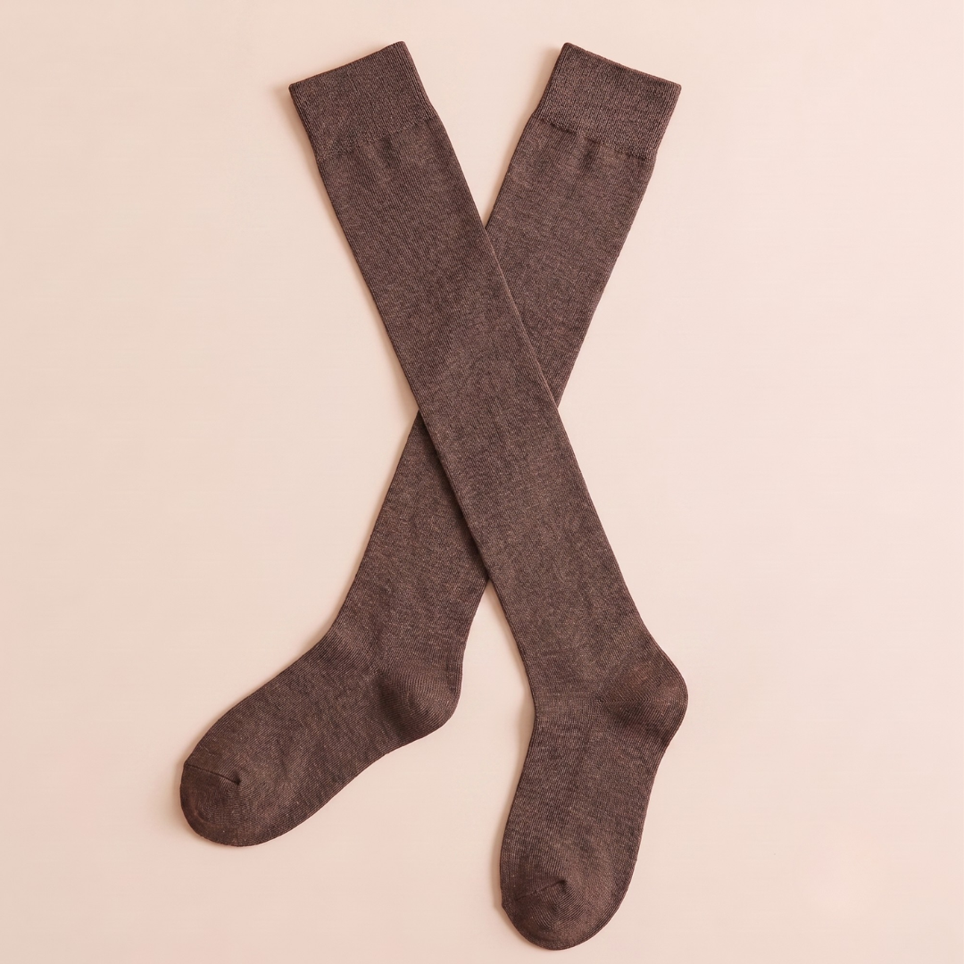 Women's knee high boot socks in dark brown, featuring a smooth ribbed knit. Two socks crossed on a neutral background.