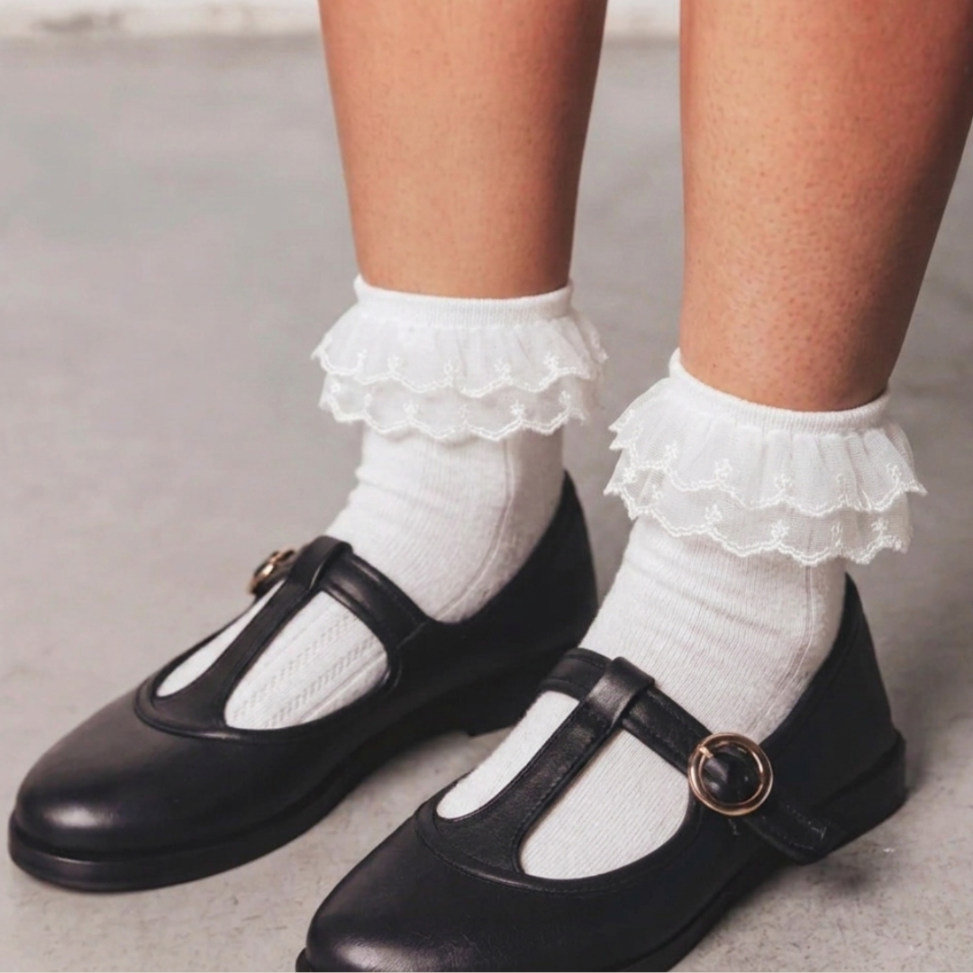 Lace ruffle socks in white with a frilly lace cuff, worn with black Mary Jane shoes.