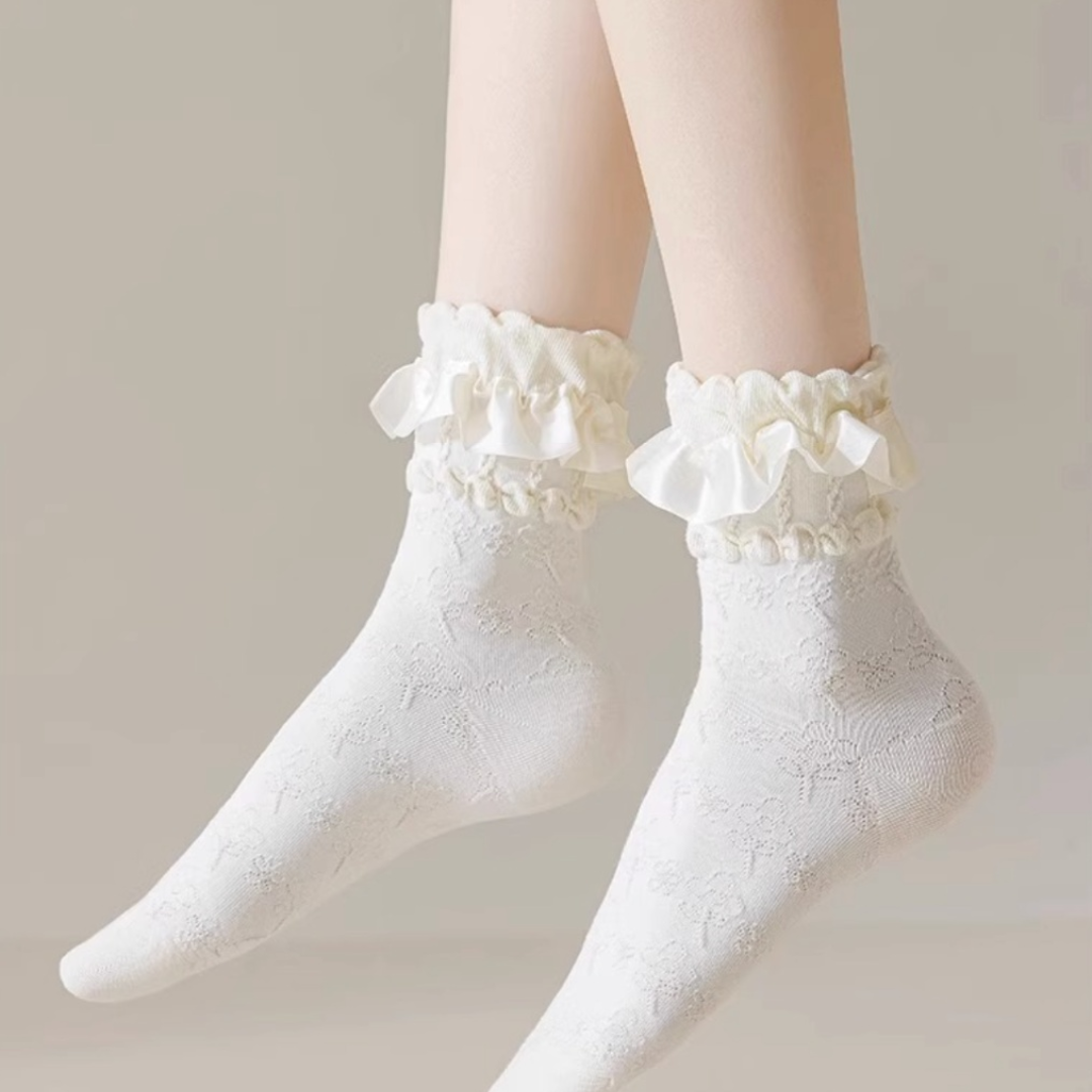 Lace socks for loafers in white cotton with a ruffled lace trim, worn on the feet, front view.