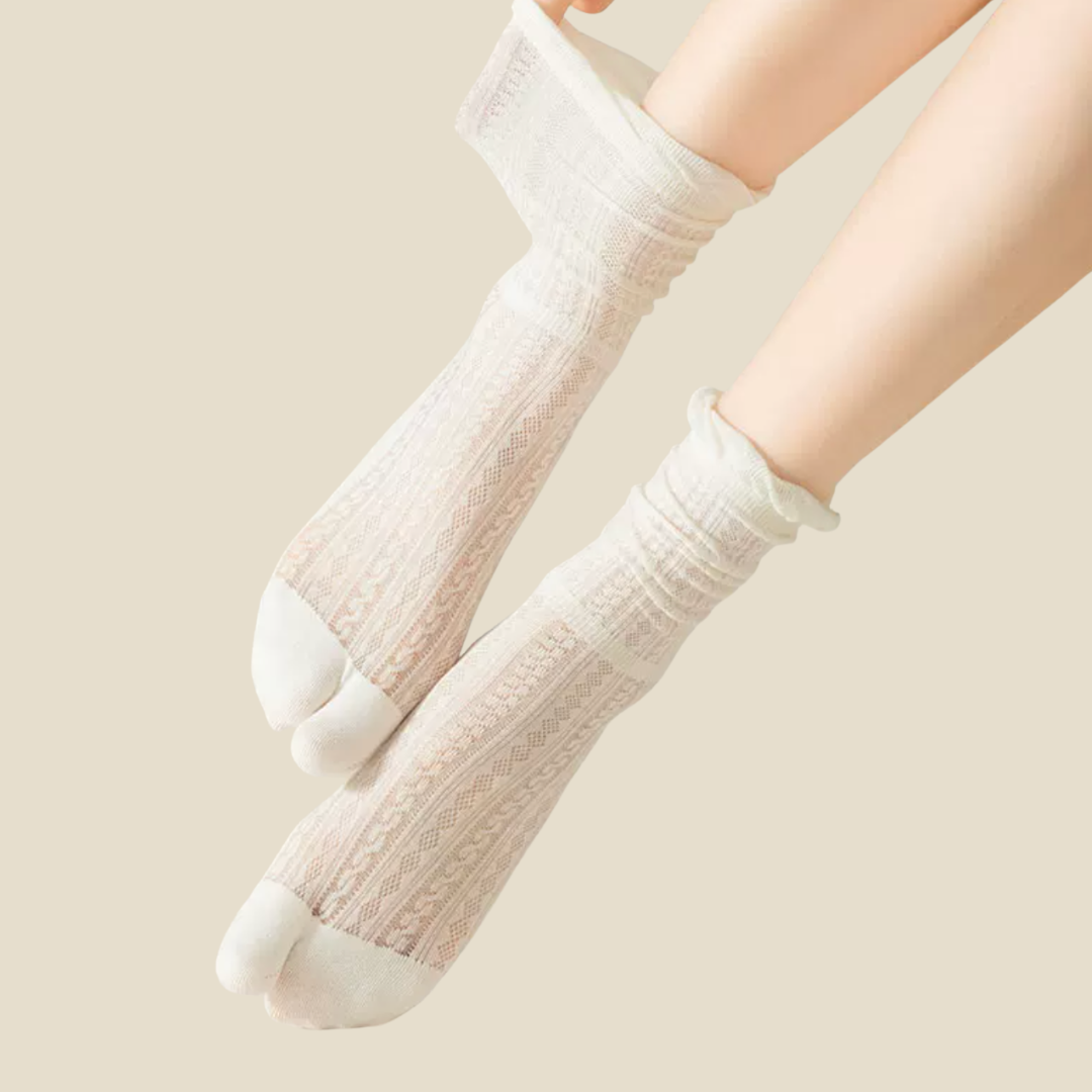 Ladies tabi socks in cream, featuring a split-toe ribbed knit. Worn on feet in a soft setting.