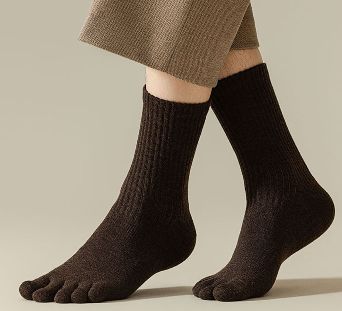 Male toe socks in black ribbed knit, featuring a snug five-toe fit. Worn on the feet with olive trousers.