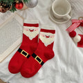 Men's Christmas socks in red with a Santa design, flat-lay pair styled with a coffee cup and ornaments.