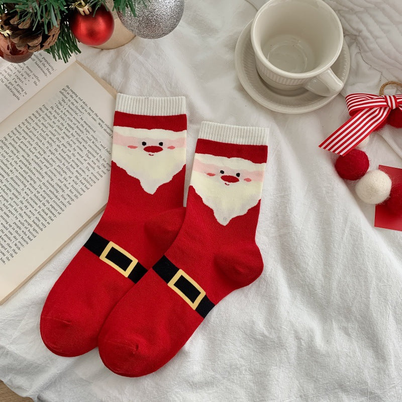 Men's Christmas socks in red with a Santa design, flat-lay pair styled with a coffee cup and ornaments.